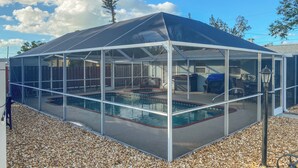 A covered swimming pool with a glass enclosure, surrounded by pebbles, and a wooden fence in the background. - 1 Mi to Beach: Nokomis Home w/ Private Pool (Nokomis)