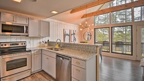 A modern kitchen with stainless steel appliances, a granite countertop, and large windows offering a view of the outdoors. - Designer Retreat w/ Pool, Golf + Beach Access! (Salem)