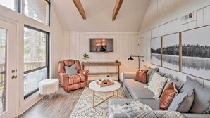 A cozy living room with a fireplace, leather armchair, and a large window. - Designer Retreat w/ Pool, Golf + Beach Access! (Salem)