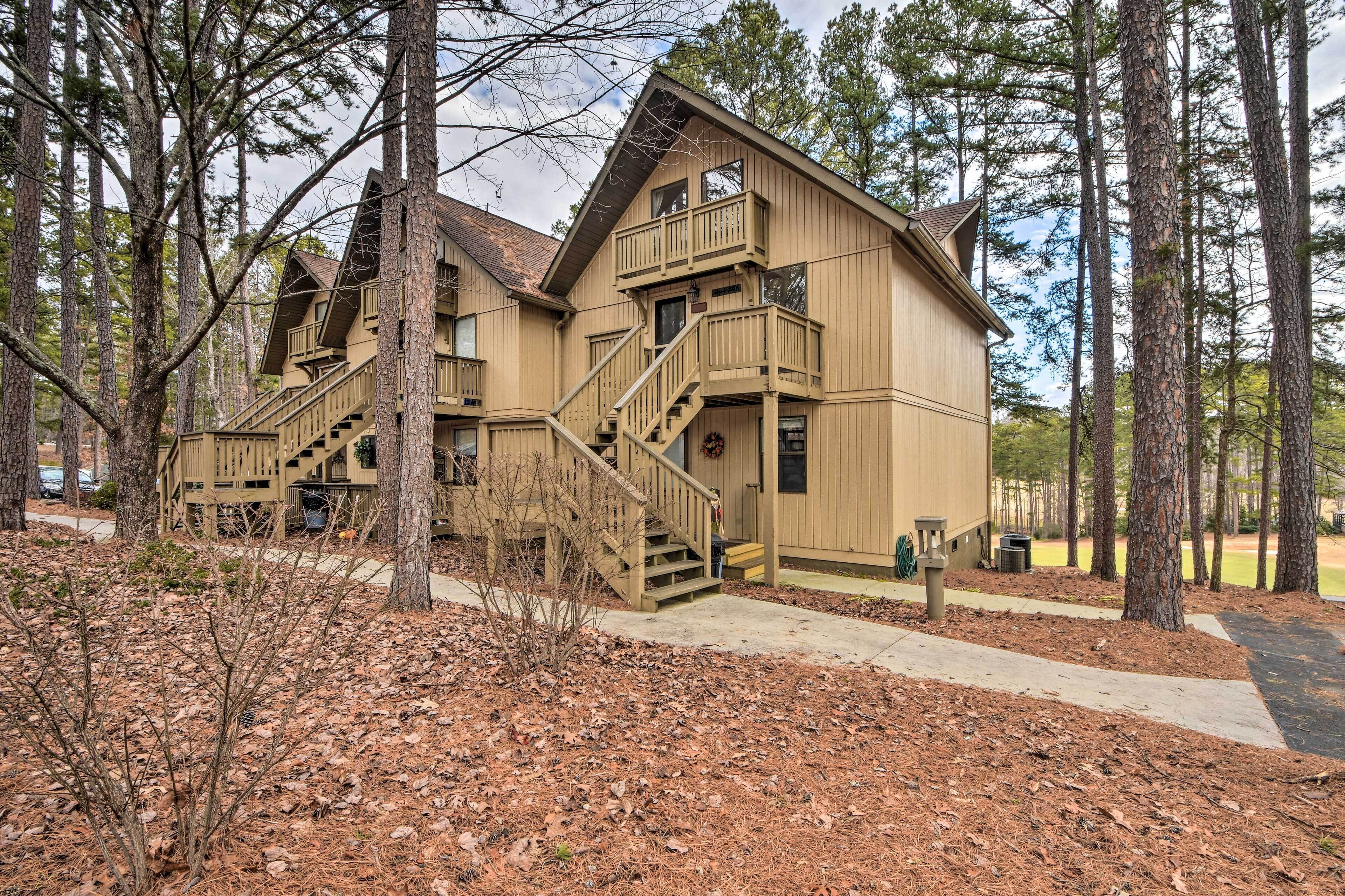 A two-story wooden lodge with a balcony and a staircase leading to the upper floor.