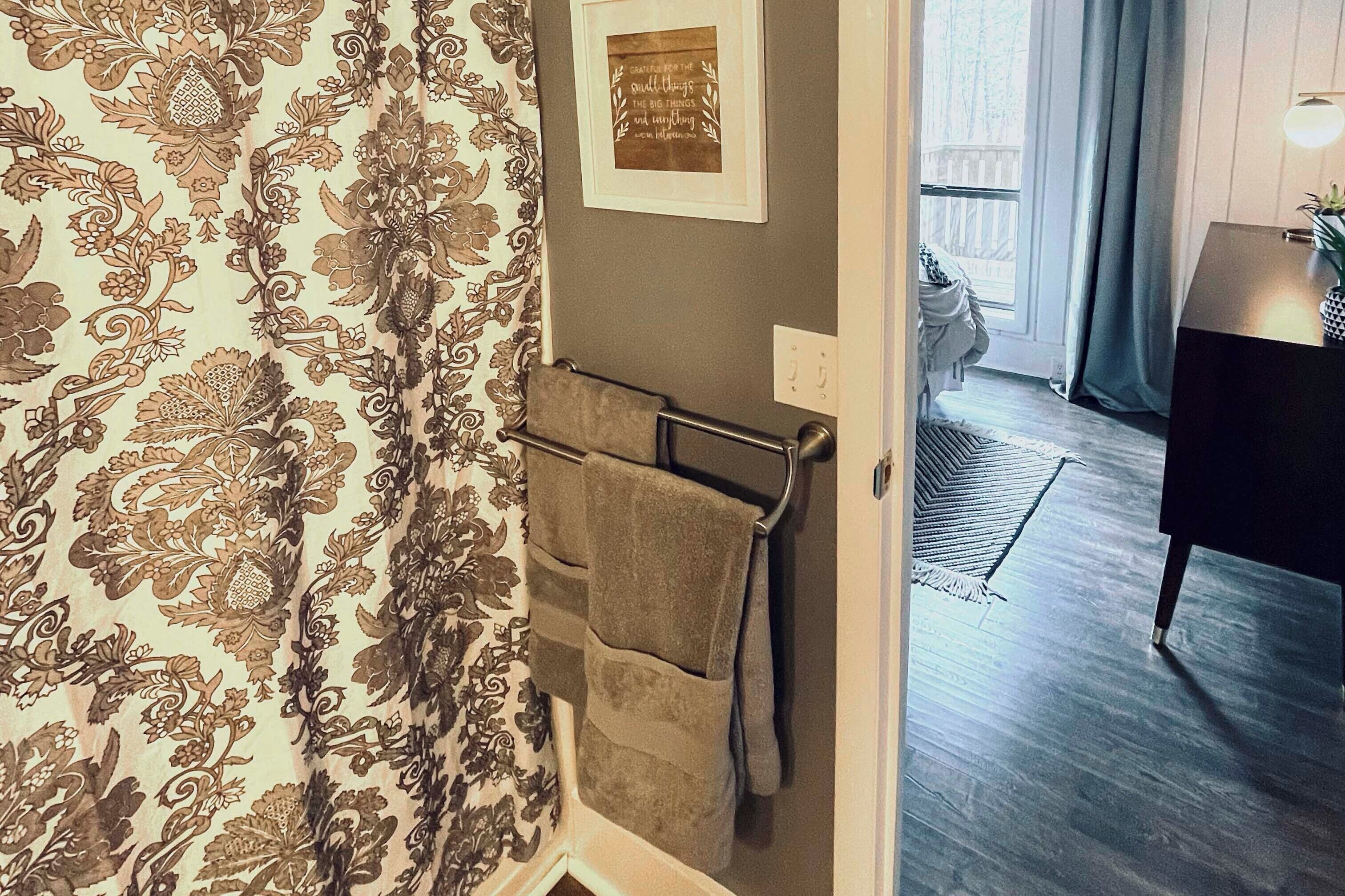 Ein Badezimmer mit gestreiftem Wandpapier, einem Handtuchhalter und einem gerahmten Zitat an der Wand.
