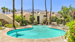 A swimming pool with a curved edge, surrounded by palm trees and a mountain backdrop. - Palm Springs Hideaway w/ Resort Amenities! (Palm Springs)