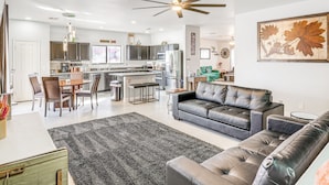 A modern kitchen with a central island, a dining area with chairs, a leather sofa, and a large artwork on the wall. - Family Home w/ Community Perks in Peoria (Peoria)