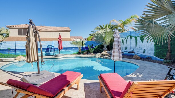 A pool area with lounge chairs and umbrellas, a mural wall, and a view of the ocean. - Family Home w/ Community Perks in Peoria (Peoria)