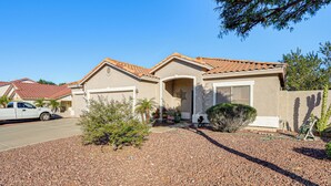 A residential house with a tiled roof, a garage, and a gravel driveway. - Family Home w/ Community Perks in Peoria (Peoria)