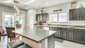 A modern kitchen with a central island, dark cabinets, and a large window providing natural light. - Family Home w/ Community Perks in Peoria (Peoria)