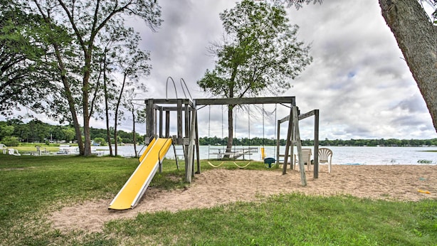 Ein Spielplatz mit Rutsche und Schaukeln in der Nähe eines Sandstrandes und eines Gewässers.