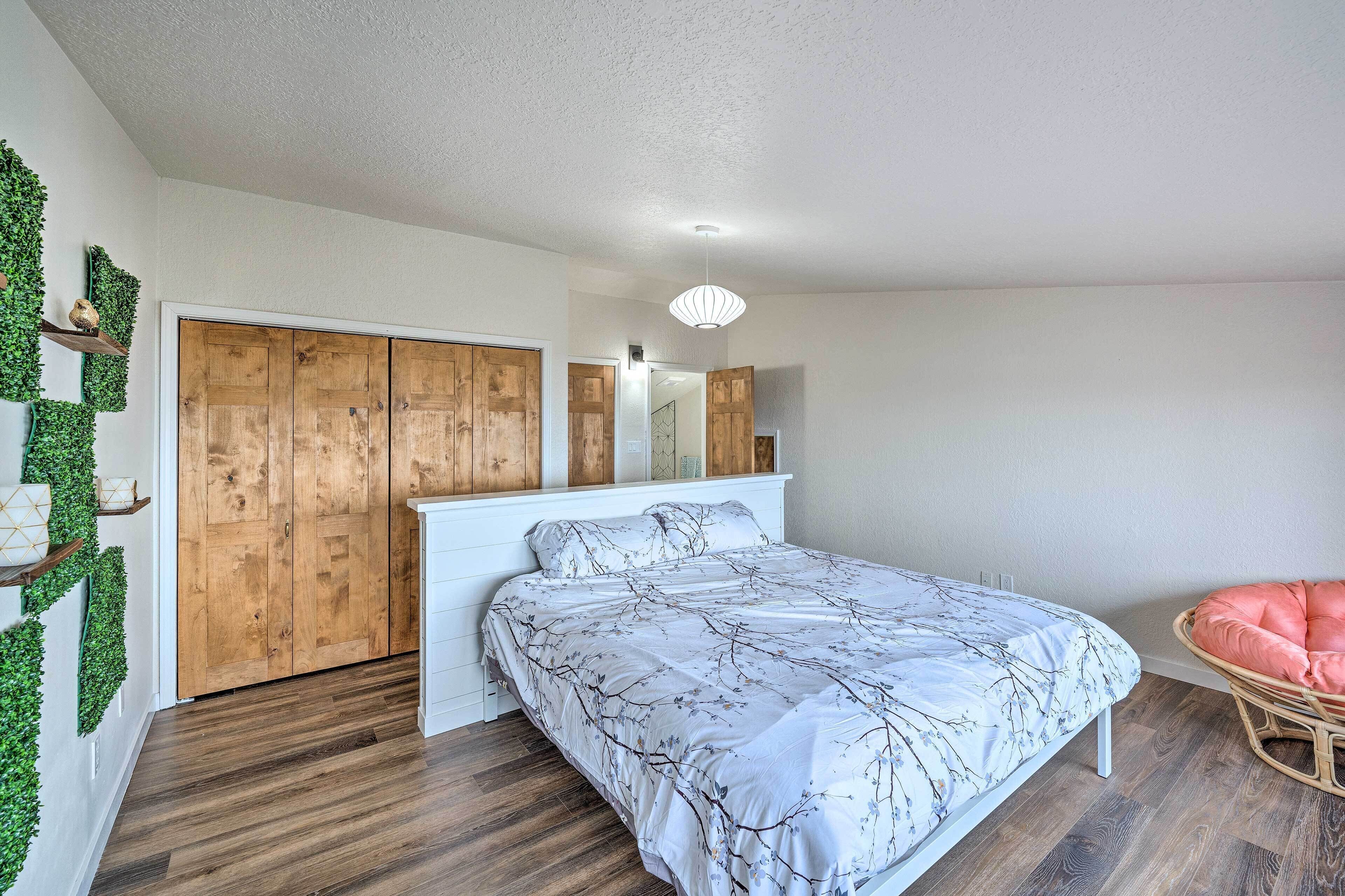 A bedroom with a bed, wooden wardrobe, and a wall-mounted shelf with greenery.