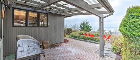A covered patio area with a grill, a view of the sea, and a well-maintained garden.