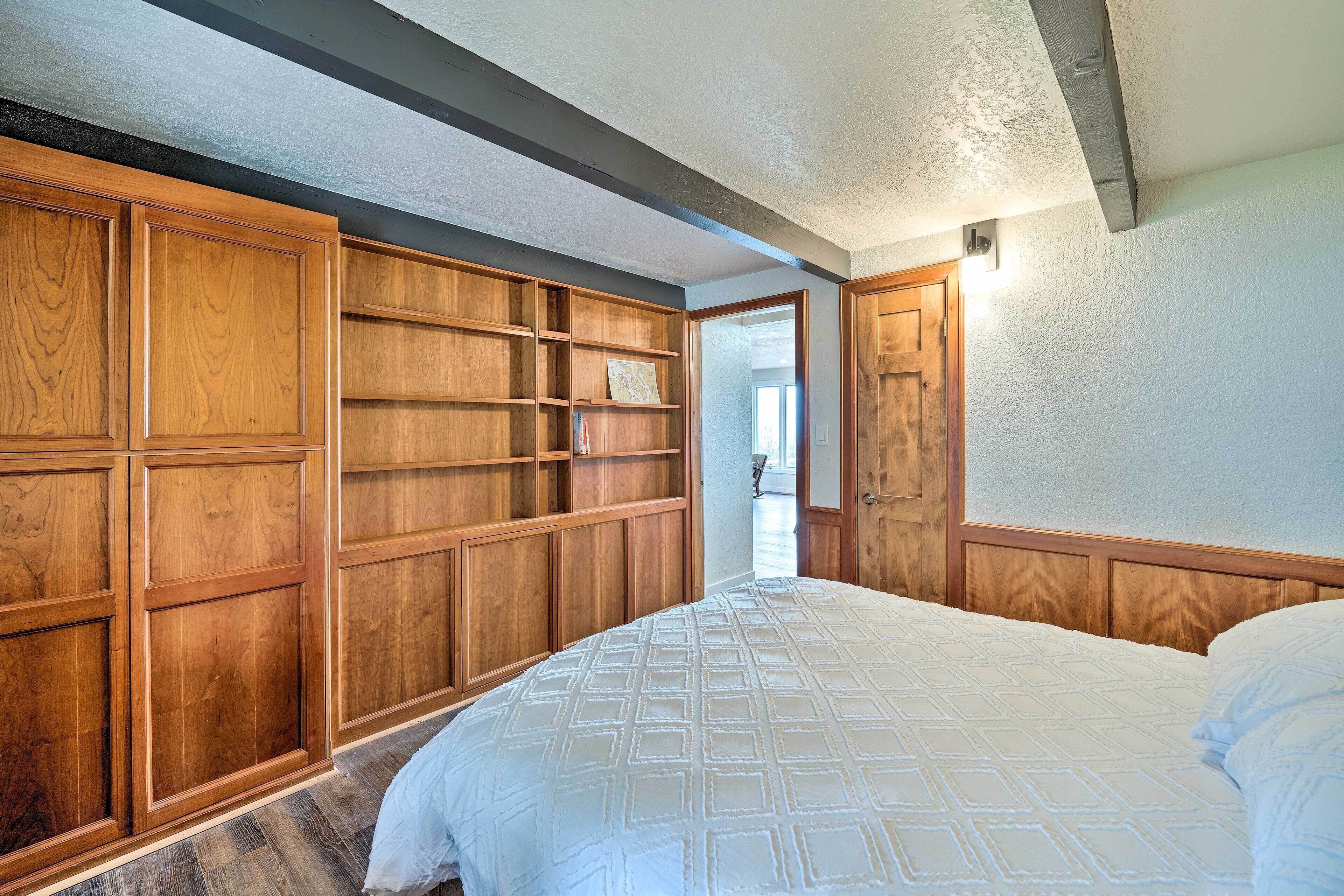 A bedroom with a large bed, wooden wardrobe, and a door leading to another room.