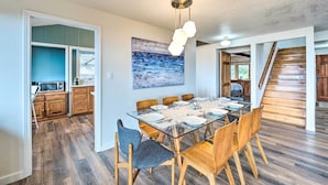 A dining area with a glass table, wooden chairs, and a modern pendant light. - Lovely Coupeville Home w/ Puget Sound Views! (Coupeville)