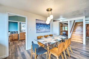 A dining area with a glass table, wooden chairs, and a modern pendant light. - Lovely Coupeville Home w/ Puget Sound Views! (Coupeville)
