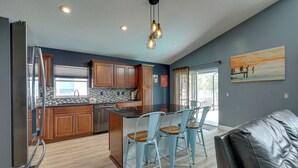 Una cucina moderna con mobili in legno, un frigorifero in acciaio inossidabile e un'area bar con sedie blu.