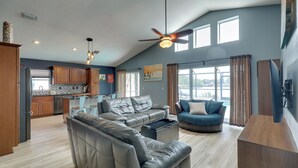 A spacious living area with a ceiling fan, a kitchen in the background, and large windows allowing natural light. - Bright Getaway w/ Ski Lake, 11 Miles to Dtwn Tampa (Brandon)