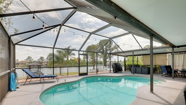 A covered swimming pool with lounge chairs, a grill, and a view of a lake. - Bright Getaway w/ Ski Lake, 11 Miles to Dtwn Tampa (Brandon)