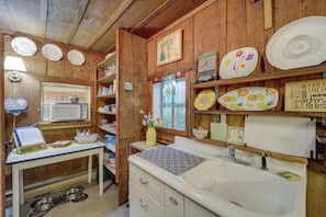 A kitchen with wooden cabinets, a microwave, a sink, and various decorative plates and bowls. - 17 Mi to Sugar Mountain: Tensies Cottage (Newland)