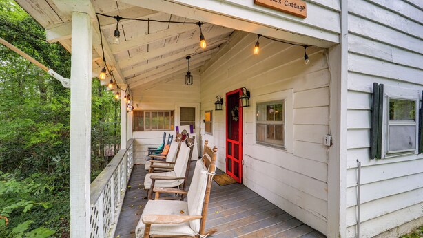 Een veranda met houten schommelstoelen en een bord met de tekst 'Tansie's Cottage'.