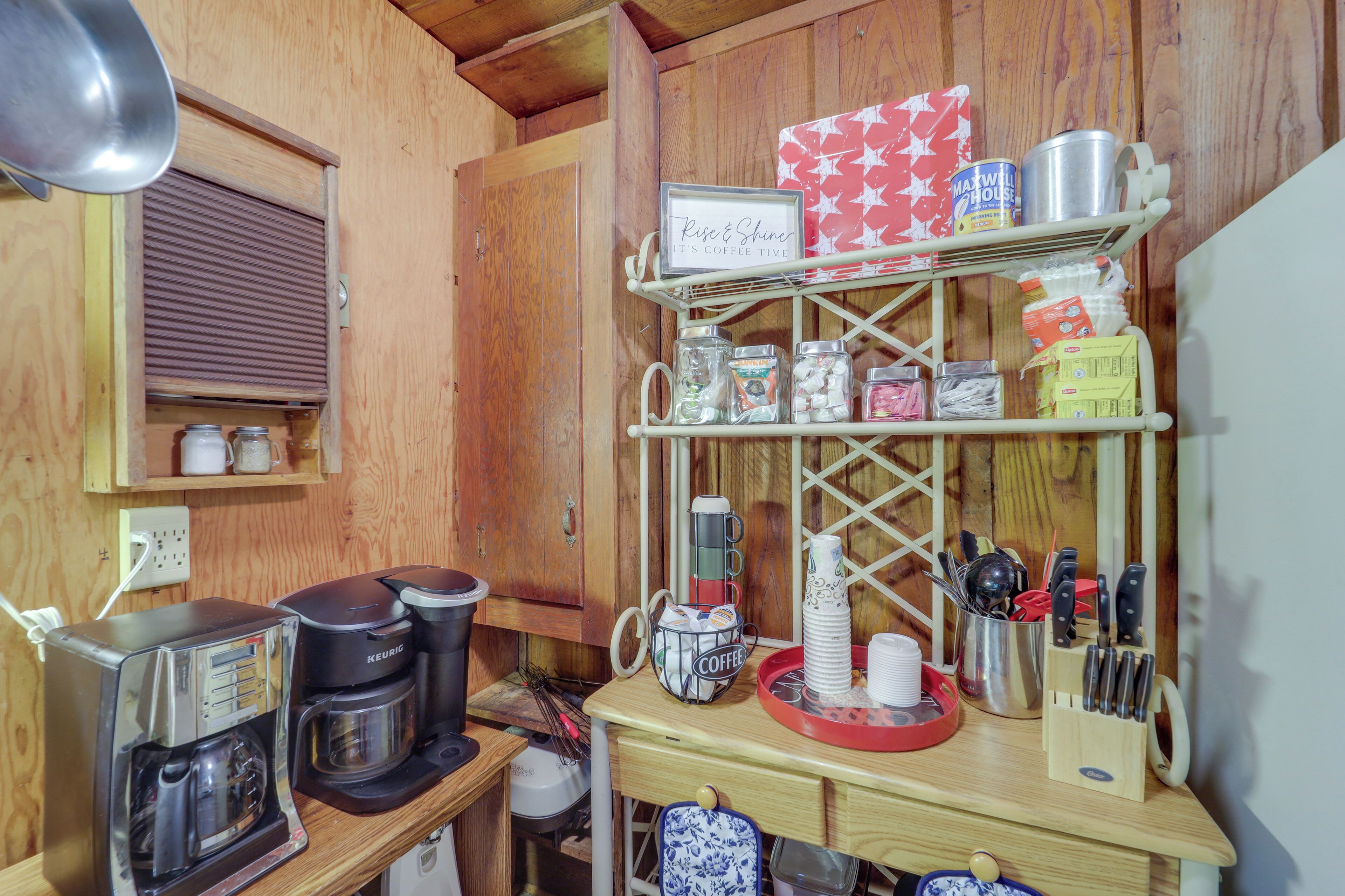 A kitchen with a coffee maker, a kettle, and a shelf with various kitchen items.