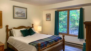 A neatly made bed with a plaid blanket, a bedside lamp, and a window with curtains. - 'the Overlook' in Massanuttens All Season Resort (McGaheysville)