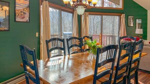 A dining area with a wooden table and chairs, a chandelier, and large windows with curtains. - 'the Overlook' in Massanuttens All Season Resort (McGaheysville)