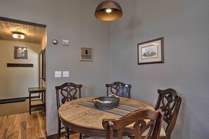 Un coin repas avec une table en bois, des chaises, un panier en osier et des tableaux encadrés accrochés au mur.
