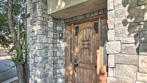 A stone-clad building with a wooden door featuring a metal latch and a small window with a metal grid.