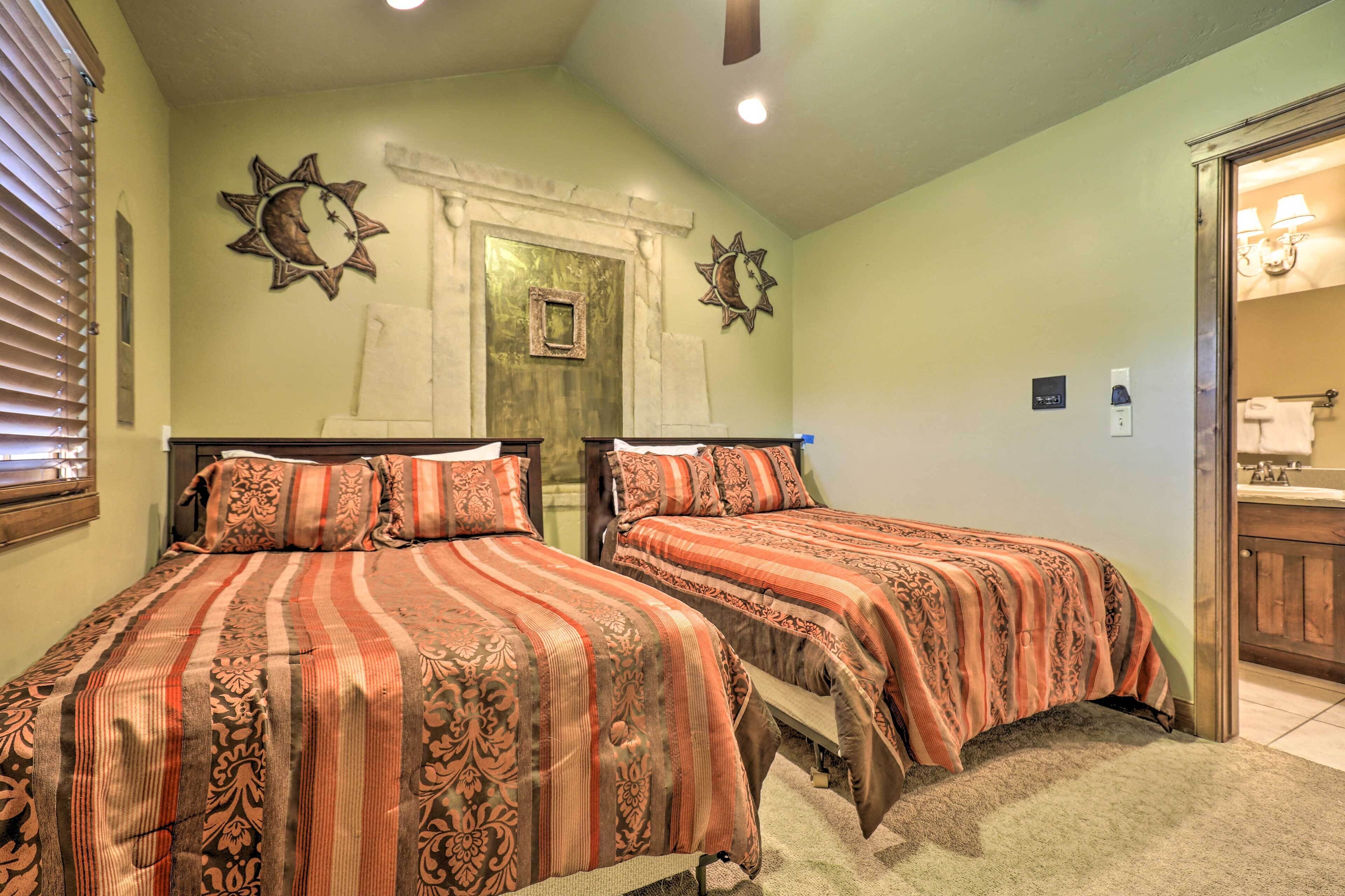 Een slaapkamer met twee bedden, een raam met zonwering en een zichtbare badkamer door een open deur.