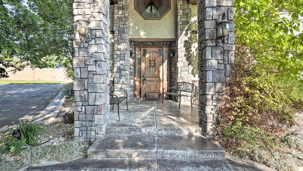 A stone entrance with a wooden door, steps, and two benches.