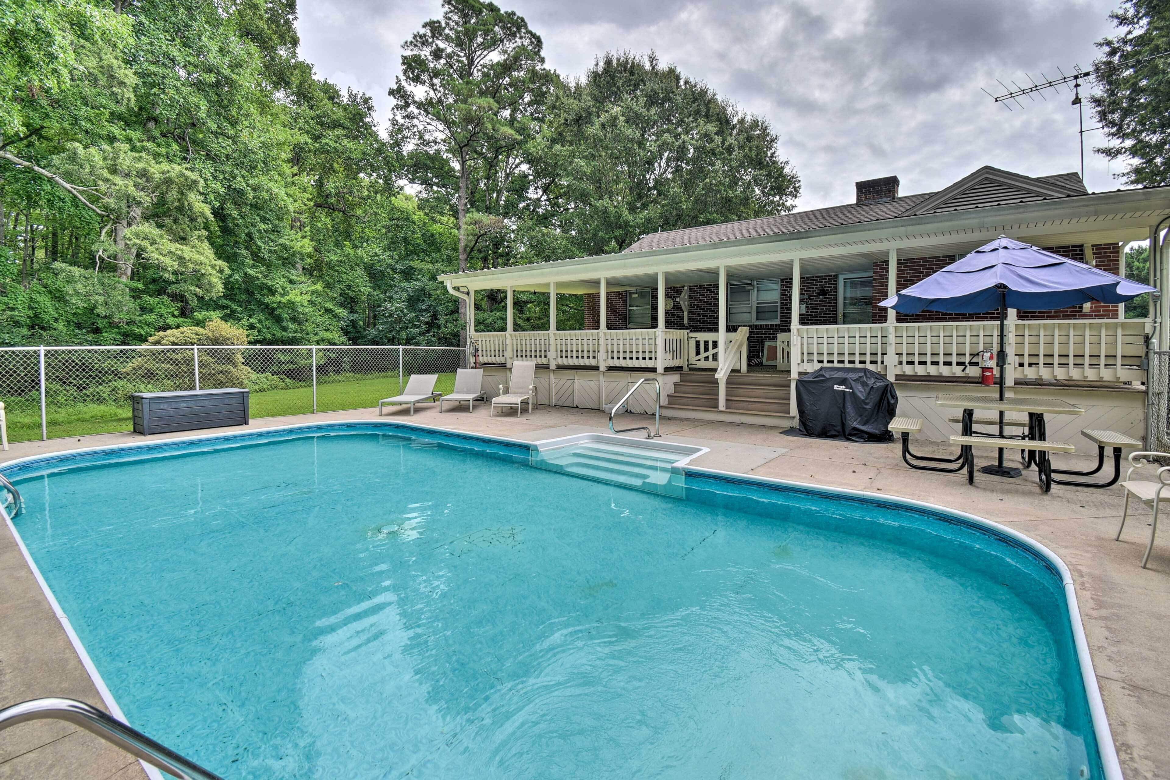 Piscina retangular com espreguiçadeiras e um deck branco.