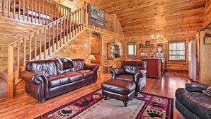 A wooden cabin interior with a staircase, leather furniture, a kitchen area, and a dining table. - Douglas Lake Cabin w/ Boat Ramp & Water Access! (Sevierville)