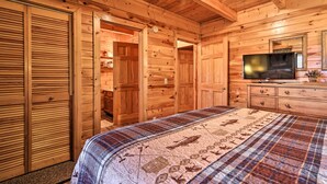 A wooden cabin bedroom with a bed, a dresser, a television, and a closet. - Douglas Lake Cabin w/ Boat Ramp & Water Access! (Sevierville)