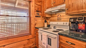 Une cuisine avec des meubles de rangement en bois, une cuisinière et une machine à café.