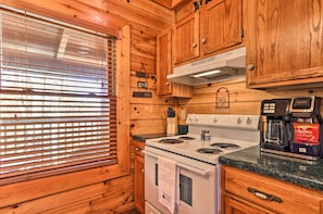 A kitchen with wooden cabinets, a stove, and a coffee maker. - Douglas Lake Cabin w/ Boat Ramp & Water Access! (Sevierville)