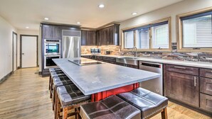 A modern kitchen with a central island, stainless steel appliances, and a large window. - Luxurious Newport Estate w/ Spa & Lighthouse Views (Newport)
