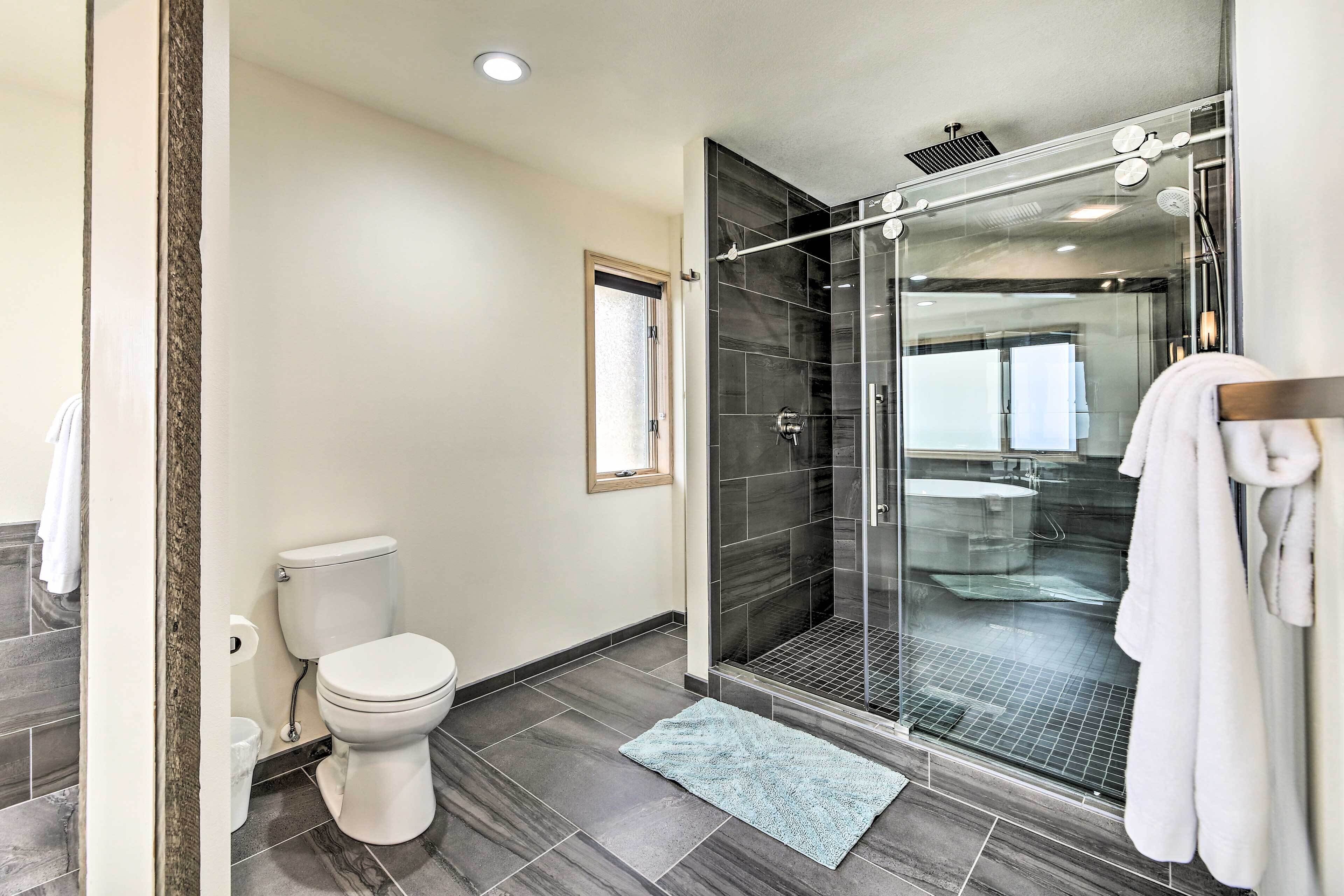 A modern bathroom with a glass-enclosed shower, a toilet, and a white towel hanging on the wall.
