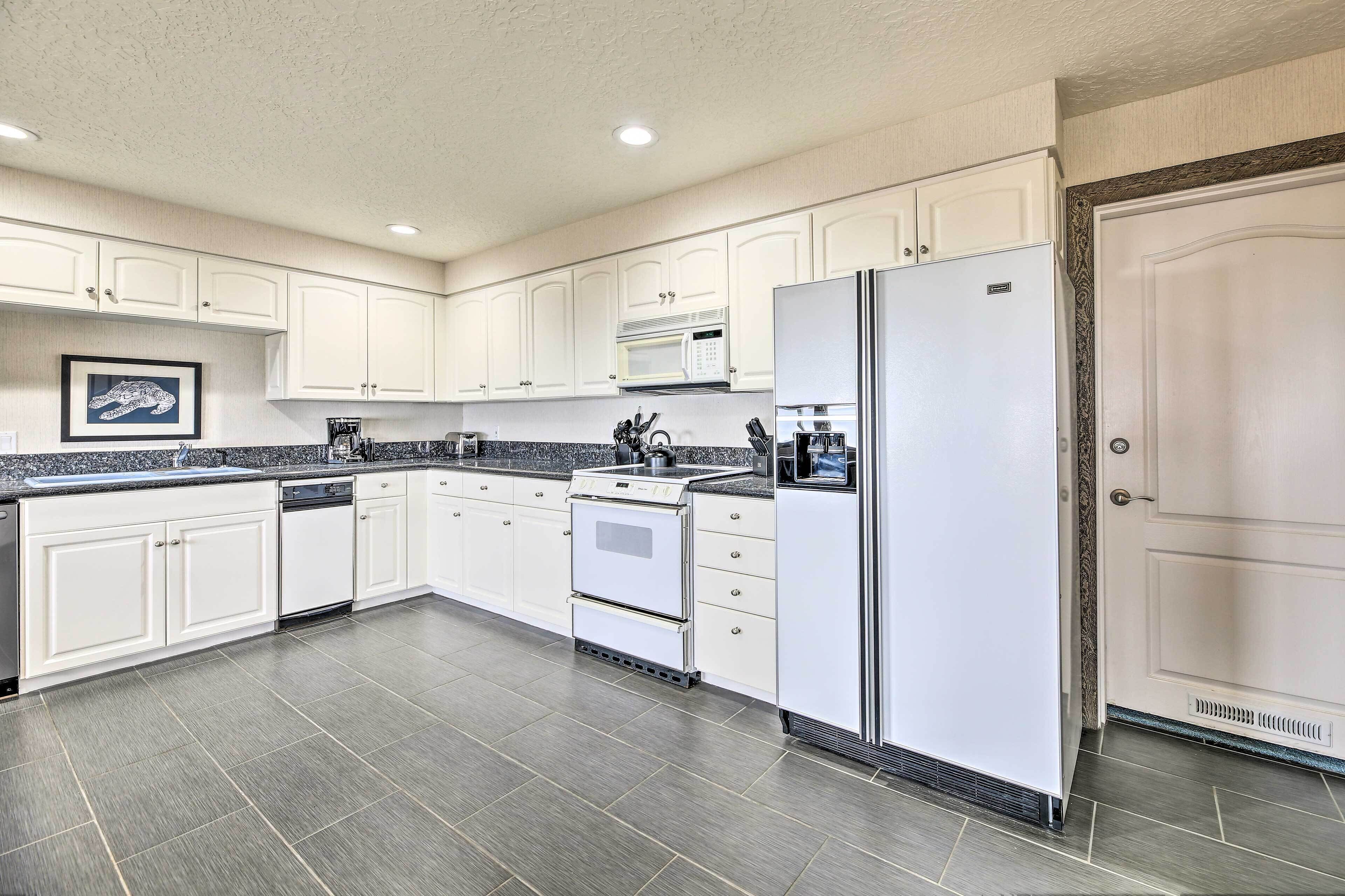 A modern kitchen with white cabinets, a stainless steel refrigerator, a microwave, and a stove.