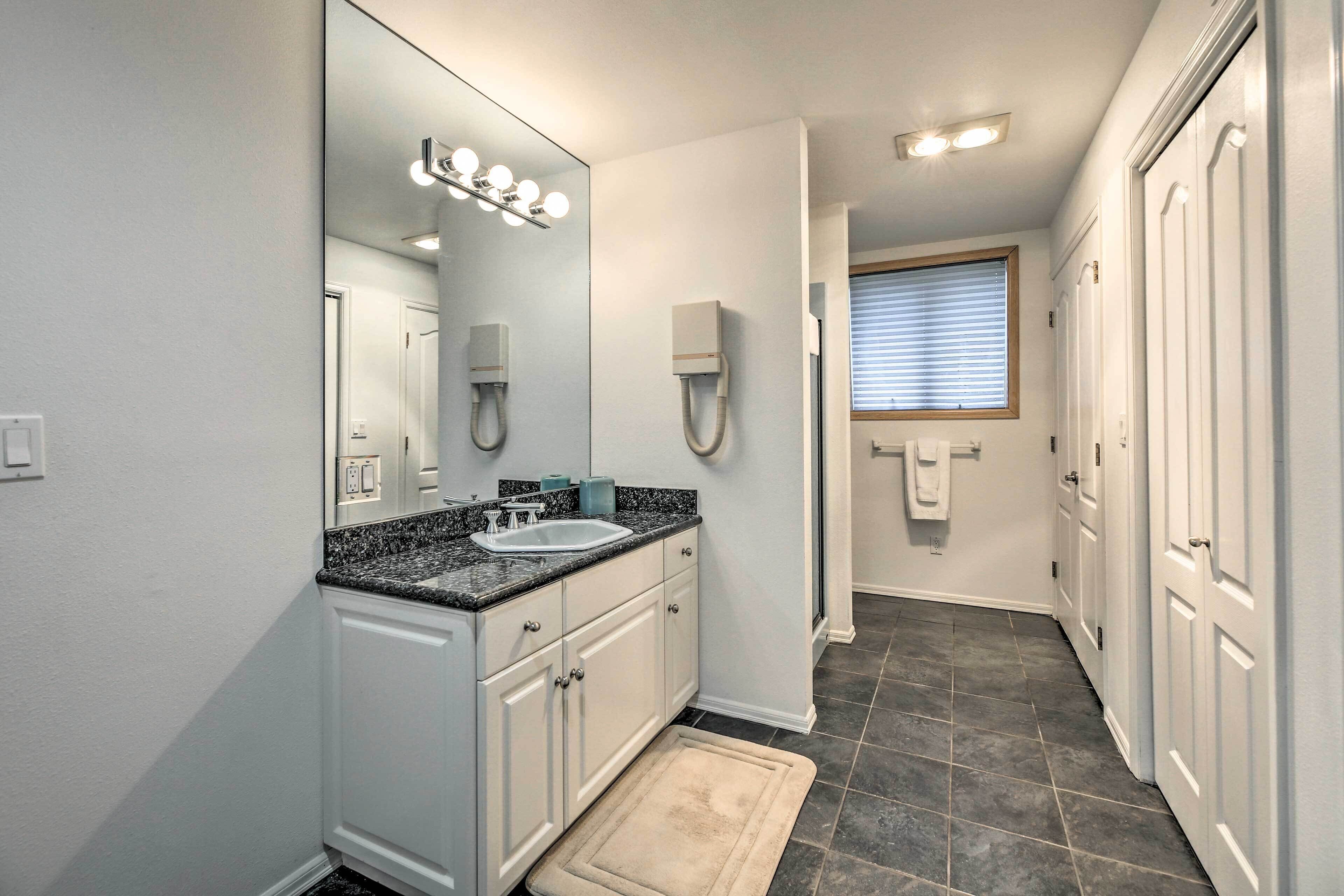 A modern bathroom with a large mirror, vanity, and a walk-in shower.