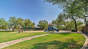 A park with a playground, including a slide and swings, surrounded by trees and a paved path. - Charming Anthem Home w/ Fire Pit, 1 Mi to Park! (Phoenix)