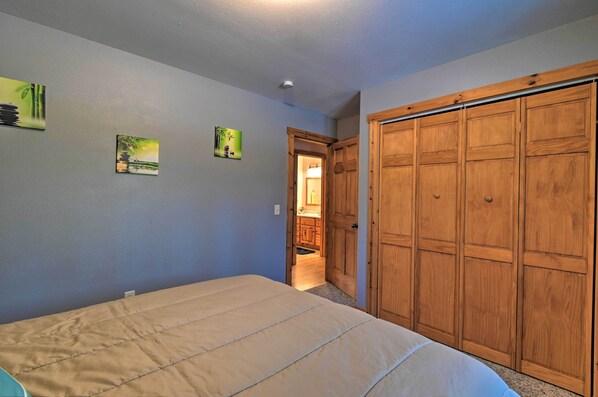 Un dormitorio con cama, armario de madera y dos cuadros en la pared.