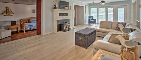 A spacious living room with a fireplace, a sofa, a coffee table, and a ceiling fan.