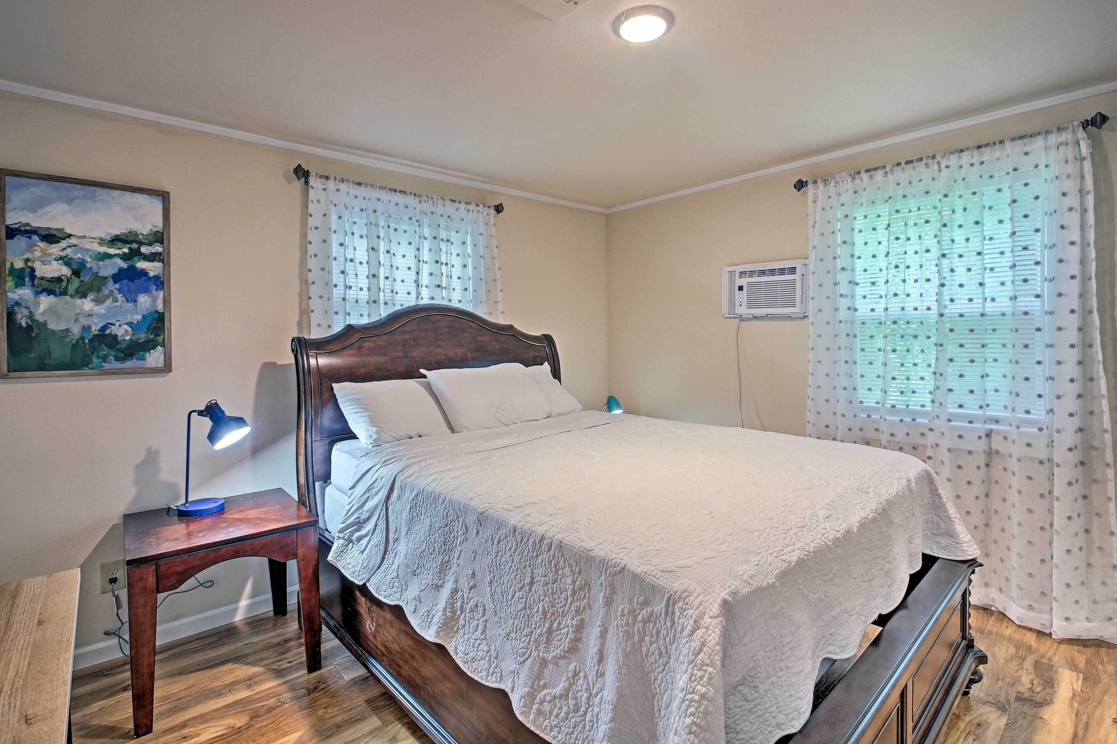 A bedroom with a wooden bed, a nightstand with a lamp, and a painting on the wall.