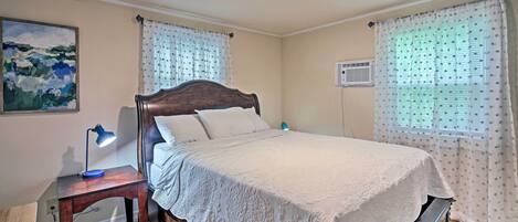 Un dormitorio con una cama de madera, una mesita de noche con una lámpara y un cuadro en la pared.