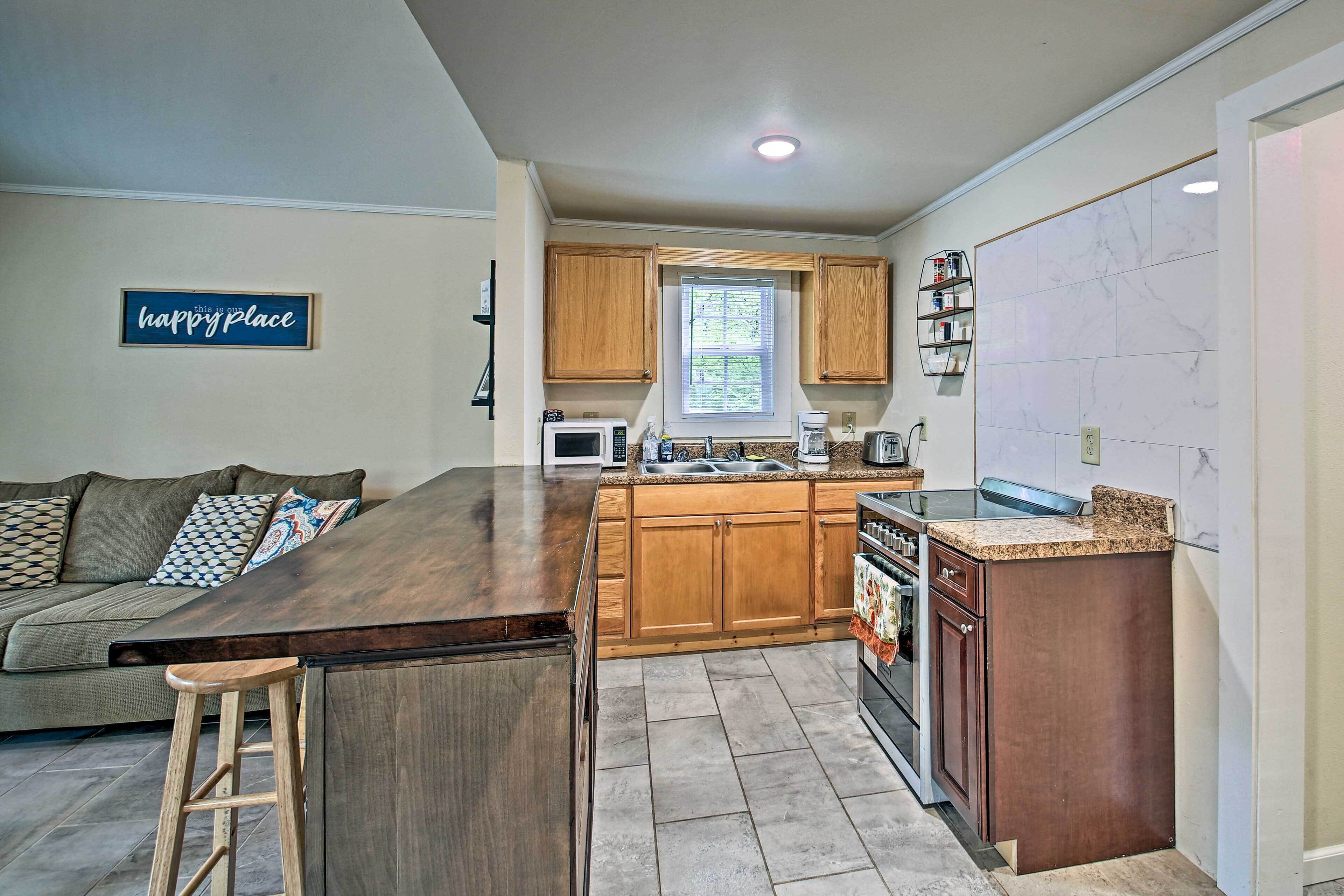 A modern kitchen with wooden cabinets, a central island, a built-in oven, and a microwave.