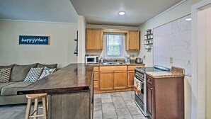 A modern kitchen with wooden cabinets, a central island, a built-in oven, and a microwave.