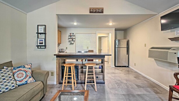 A modern kitchen with a bar area, a refrigerator, and a dining area with a couch and stools.