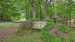 A sign for Hollywood Park surrounded by trees and a gazebo.