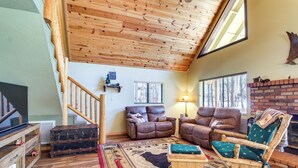 A cozy living room with a wooden ceiling, a fireplace, and a large window. - 9 Mi to Rainbow Lake: Woodsy Pinetop Cabin w/ Deck (Pinetop)