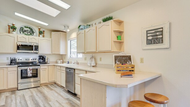 A modern kitchen with light wood cabinets, stainless steel appliances, and a central island with stools. - Hike, Sled & Snowshoe! Family Retreat in Payson (Payson)