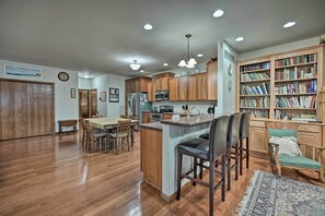 Enjoy meals and relaxation in this well-appointed kitchen and dining area, featuring a dining table for four, a bar area, and a bookshelf.