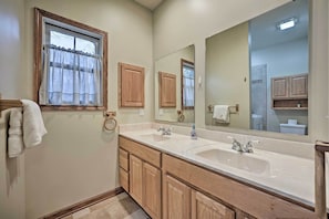 Bathroom features a double sink vanity, wooden cabinetry, and a large mirror.